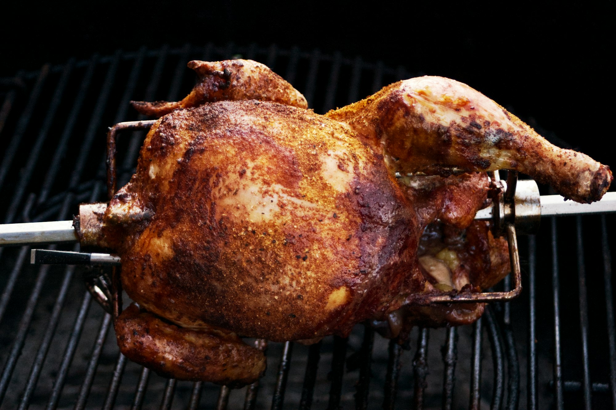 Pollos girando y dorándose en el spiedo sobre las brasas